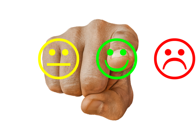 Imagem de uma mão ao centro apontando para um emoji verde sorridente. À direita um emoji amarelo e à esquerda, um emoji vermelho instatisfeito.