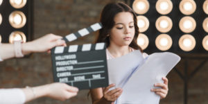 Mão segurando claquete, menina segurando script. Frases bom atendimento ao cliente