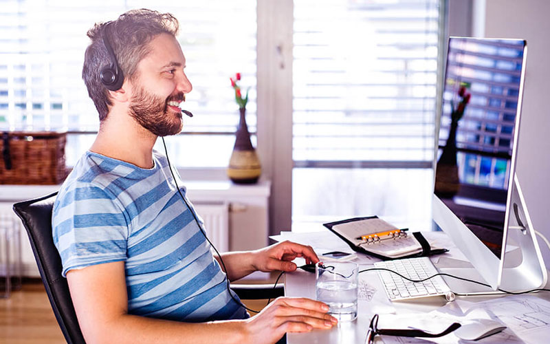 Foto homem com headset em videoconferência no seu Home Office.