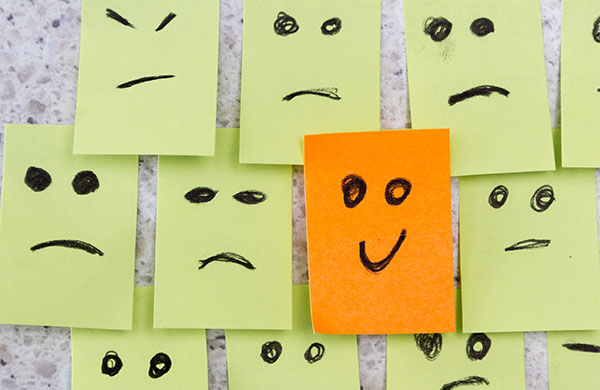 Fotos Post Its de mau humor e um post it sorridente.