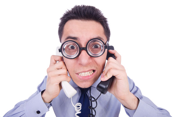 Imagem de homem atendendo dois telefones, desafios de suporte de TI em tempos de COVID-19.