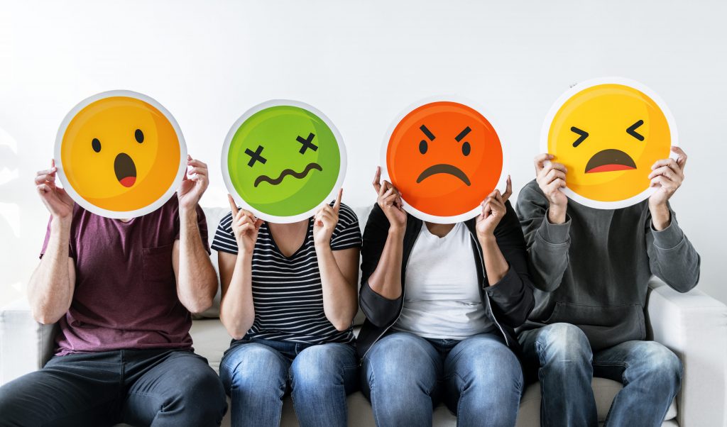 Foto pessoas segurando máscaras de emojis insatisfeitos, desafios de suporte de TI em tempos de COVID-19.
