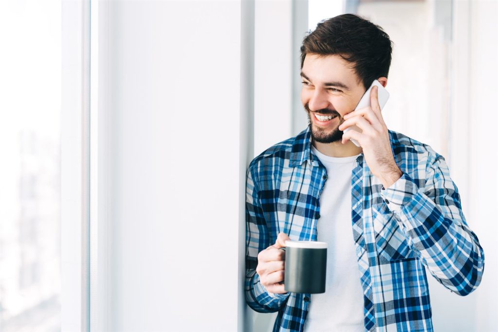 Imagem de homem falando sorridente ao telefone. Aumentar a satisfação dos clientes em tempos de crise