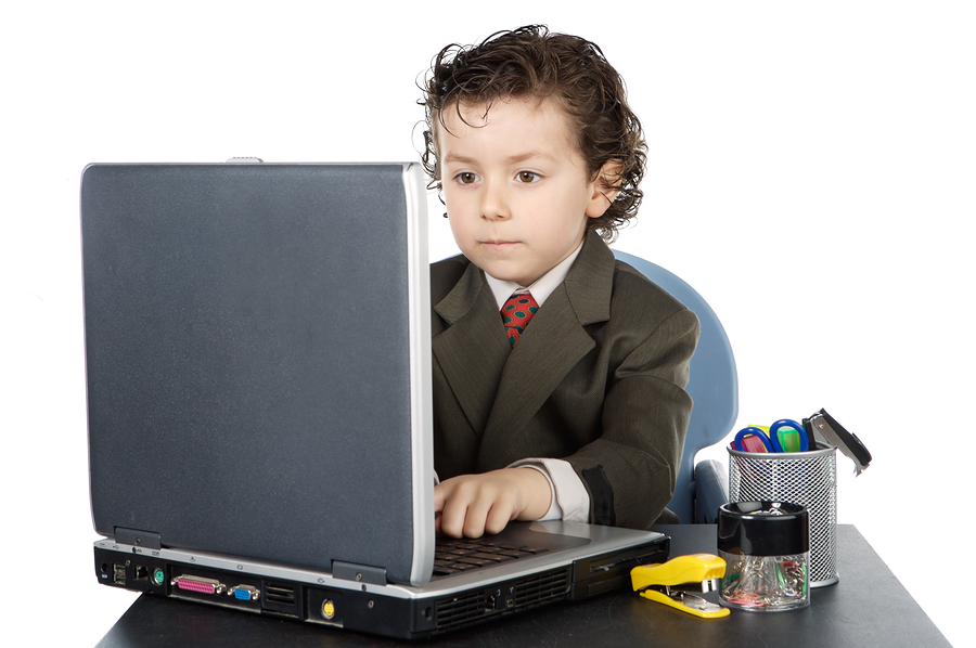 Criança vestindo terno e gravata à frente de laptop.