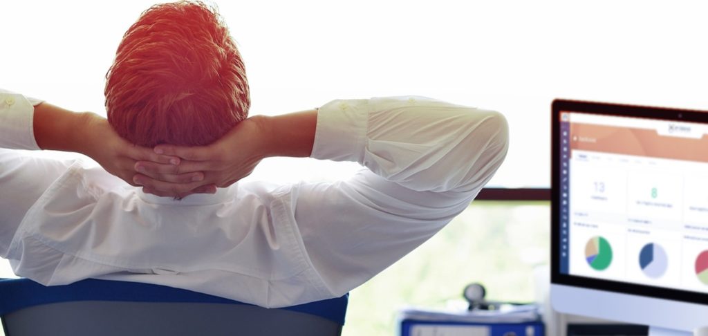 Homem em posição de relaxamento sentado à frente de computador com a dashboard do Milldesk