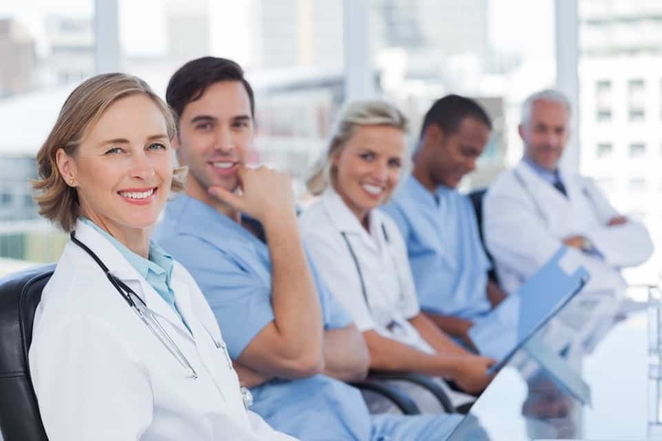 Equipe médica sorrindo, atendimento ao cliente na área da saúde.