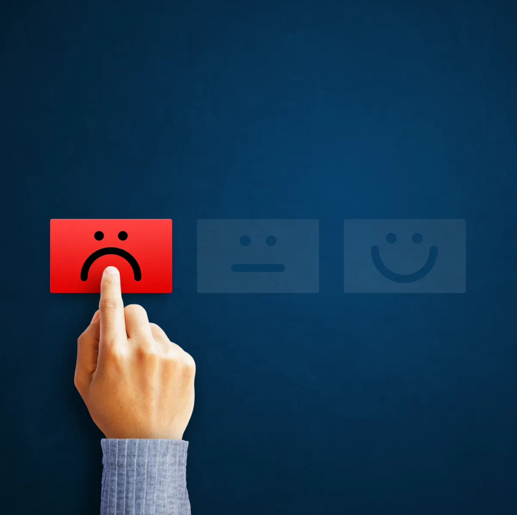 Mão apontando para emoji insatisfeito. Experiência ruim de atendimento ao cliente