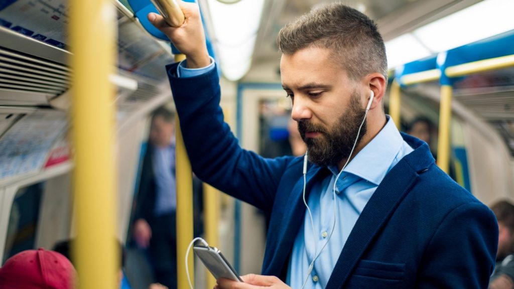 Homem em pé no ônibus ouvindo podcasts sobre atendimento ao cliente e tecnologia.